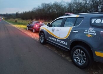 Policiais militares do Tático Ostensivo Rodoviário ao lado de viatura em rodovia durante ação que resultou na prisão de homem por sequestro e extorsão.