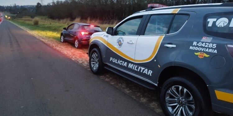 Policiais militares do Tático Ostensivo Rodoviário ao lado de viatura em rodovia durante ação que resultou na prisão de homem por sequestro e extorsão.