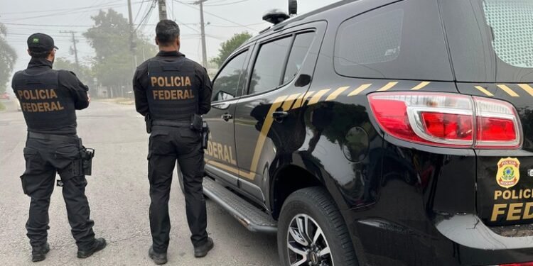 Policiais federais durante operação contra quadrilha de roubos de cargas em rua residencial.