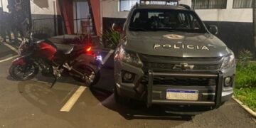 Motocicleta Honda Twister vermelha recuperada pela Polícia Militar em Sumaré após furto de motocicleta, ao lado de viatura do BAEP estacionada em frente ao Plantão Policial.