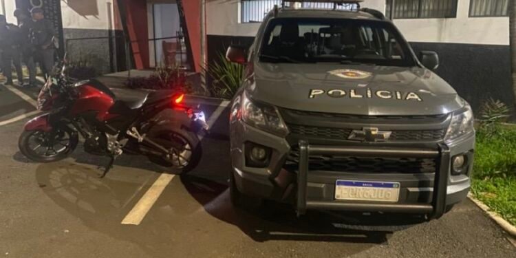 Motocicleta Honda Twister vermelha recuperada pela Polícia Militar em Sumaré após furto de motocicleta, ao lado de viatura do BAEP estacionada em frente ao Plantão Policial.