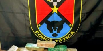 Força Tática apreende 11 kg de crack em Santa Bárbara d’Oeste durante ocorrência de tráfico internacional de drogas com grande quantidade de entorpecentes apreendidos. #PraCegoVer: A imagem mostra tijolos de crack embalados em plástico sobre uma superfície, ao lado de porções de cocaína fracionadas, balanças digitais e uma viatura da Polícia Militar ao fundo durante operação noturna.