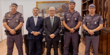 cooperação entre GAECO e PM #PraCegoVer: imagem mostra reunião institucional na sede do Ministério Público de São Paulo com representantes do GAECO e da Polícia Militar sentados em mesa de trabalho debatendo estratégias de combate ao crime organizado.