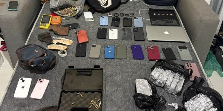 casa cofre com 96 celulares roubados apreendidos pela Polícia Militar em Paraisópolis #PraCegoVer Policiais militares organizam dezenas de celulares e notebooks apreendidos sobre uma mesa em imóvel simples na comunidade