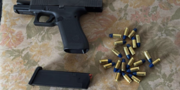 operação Jandaia contra célula do PCC no interior de SP #PraCegoVer: imagem mostra arma de fogo aberta de forma segura e munições de ponta azul encima de uma cama, provavel lugar das buscas e apreensões.