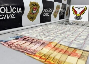 dise prende traficante no jardim aline #PraCegoVer: sobre uma superfície estão diversas porções de drogas embaladas organizadas em fileiras, além de notas de dinheiro em primeiro plano, com painel da Polícia Civil e identificação da DISE de Americana ao fundo