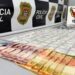 dise prende traficante no jardim aline #PraCegoVer: sobre uma superfície estão diversas porções de drogas embaladas organizadas em fileiras, além de notas de dinheiro em primeiro plano, com painel da Polícia Civil e identificação da DISE de Americana ao fundo