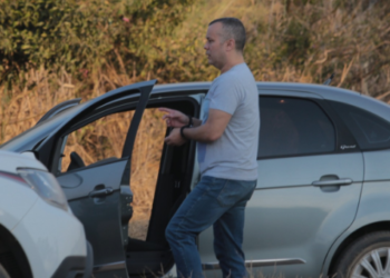 Condenação por feminicídio em Americana com pena de 34 anos em regime fechado #PraCegoVer Imagem mostra reconstituição do crime com a polícia cientifica, onde aparece Hélio ao lado do carro usado, apontando dedo algemado explicando como foi cada detalhe do crime