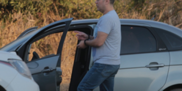 Condenação por feminicídio em Americana com pena de 34 anos em regime fechado #PraCegoVer Imagem mostra reconstituição do crime com a polícia cientifica, onde aparece Hélio ao lado do carro usado, apontando dedo algemado explicando como foi cada detalhe do crime