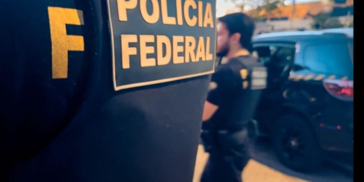 operação Cruzador contra abuso sexual infantil e apologia ao nazismo #PraCegoVer agente da Polícia Federal com colete institucional ao lado de viatura durante operação policial