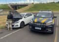 PRF recupera carro roubado na Bahia durante fiscalização em São José do Rio Preto #PraCegoVer policial rodoviário federal verifica veículo branco parado ao lado de viatura da PRF em rodovia