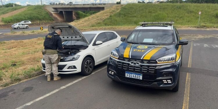 PRF recupera carro roubado na Bahia durante fiscalização em São José do Rio Preto #PraCegoVer policial rodoviário federal verifica veículo branco parado ao lado de viatura da PRF em rodovia
