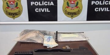 polícia civil prende traficante no jardim da mata #PraCegoVer: sobre uma mesa estão dois simulacros de arma de fogo, uma algema rosa, dinheiro em notas e moedas, além de embalagens e ao fundo painel da Polícia Civil do Estado de São Paulo