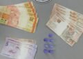 polícia militar prende traficante com cocaína #PraCegoVer: imagem mostra notas de dinheiro organizadas por valores, pequenos recipientes plásticos com droga ao centro e o emblema da Polícia Militar do Estado de São Paulo na parte superior