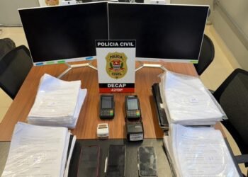 golpe contra idosos em clínica odontológica em SP #PraCegoVer: mesa com apreensões da clínica odontológica com movimentação policial durante investigação de fraudes contra idosos.