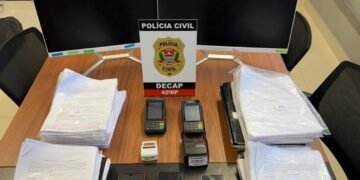 golpe contra idosos em clínica odontológica em SP #PraCegoVer: mesa com apreensões da clínica odontológica com movimentação policial durante investigação de fraudes contra idosos.