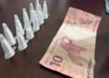 homem preso com cocaína na operação Impacto em Cosmópolis #PraCegoVer: imagem mostra pinos de cocaína em fileira dupla contendo 11 pinos e uma nota de R$10 encima de uma mesa na delegacia