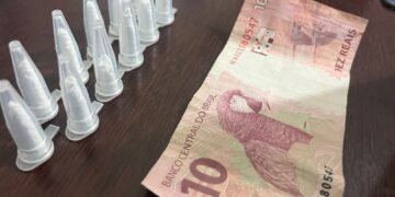 homem preso com cocaína na operação Impacto em Cosmópolis #PraCegoVer: imagem mostra pinos de cocaína em fileira dupla contendo 11 pinos e uma nota de R$10 encima de uma mesa na delegacia