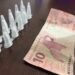 homem preso com cocaína na operação Impacto em Cosmópolis #PraCegoVer: imagem mostra pinos de cocaína em fileira dupla contendo 11 pinos e uma nota de R$10 encima de uma mesa na delegacia