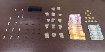 Polícia Militar flagra tráfico de drogas no Balneário Riviera em Americana #PraCegoVer: viatura da Polícia Militar em rua residencial durante ação policial na região da Praia Azul, com agentes em patrulhamento e material apreendido apresentado em uma mesa na delegacia pinos de cocaína, pedras de crack em plásticos pretos, ziplock com maconhas fracionadas um celular e dinheiro fracionados em diversas notas em destaque