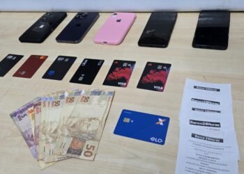 DIG prende trio por fraude contra idosos #PraCegoVer celulares, cartões bancários, dinheiro em espécie e comprovantes de atendimento bancário aparecem sobre uma mesa após apreensão feita pela Polícia Civil em ocorrência de fraude contra idosos