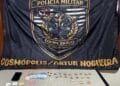 PM prende homem por trafico de drogas #PraCegoVer imagem mostra drogas, dinheiro e um celular apreendidos sobre uma mesa, com bandeira da Polícia Militar ao fundo