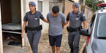 dois procurados capturados em Cosmopolis #PraCegoVer imagem criada por inteligência artificial mostra uma policial militar feminina e um policial militar conduzindo um procurado após ação rápida em bairro residencial, com viatura ao lado e uma casa ao fundo