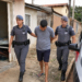 dois procurados capturados em Cosmopolis #PraCegoVer imagem criada por inteligência artificial mostra uma policial militar feminina e um policial militar conduzindo um procurado após ação rápida em bairro residencial, com viatura ao lado e uma casa ao fundo
