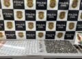 DISE apreende drogas na operação Gueleri em Sumaré #PraCegoVer mesa com porções de drogas, dinheiro, celulares e balanças apreendidas em frente a painel da Polícia Civil e placa da DISE de Americana