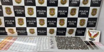DISE apreende drogas na operação Gueleri em Sumaré #PraCegoVer mesa com porções de drogas, dinheiro, celulares e balanças apreendidas em frente a painel da Polícia Civil e placa da DISE de Americana