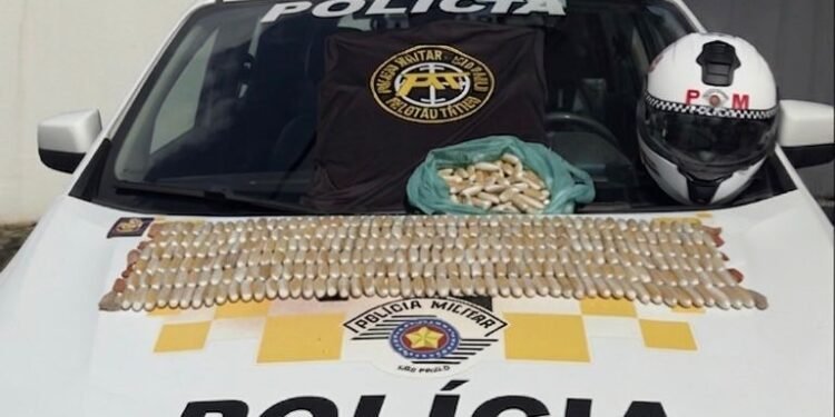 tráfico em ônibus na Marginal Tietê #PraCegoVer imagem mostra uma viatura da Polícia Militar com centenas de cápsulas de cocaína organizadas sobre o capô, além de uma camiseta do Policiamento de Trânsito, um capacete policial e uma sacola com mais cápsulas apreendidas