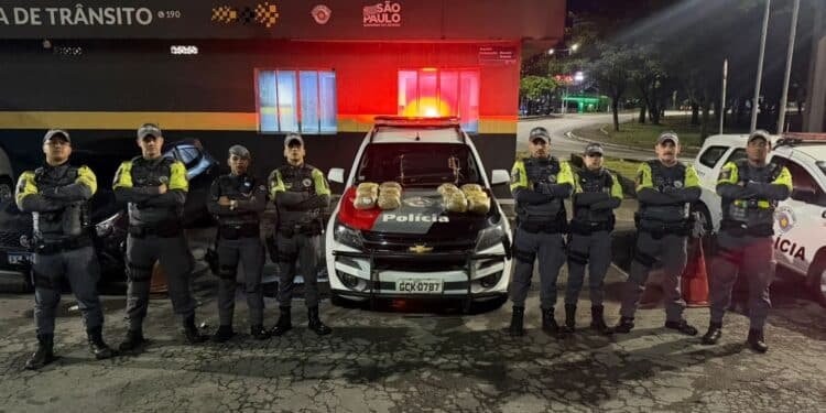PM prende boliviano por tráfico internacional na Marginal Tietê #PraCegoVer: a imagem mostra uma equipe da Polícia Militar de Trânsito posicionada em frente à base policial na Marginal Tietê, em São Paulo, ao lado de viaturas e com tabletes de maconha expostos sobre o capô de um veículo oficial durante a Operação Fim da Linha.
