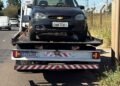 GCM prende homem após perseguição em Americana #PraCegoVer carro preto sobre caminhão-guincho em avenida, com postes, fios elétricos, céu azul e área de mato ao lado da via