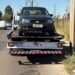 GCM prende homem após perseguição em Americana #PraCegoVer carro preto sobre caminhão-guincho em avenida, com postes, fios elétricos, céu azul e área de mato ao lado da via