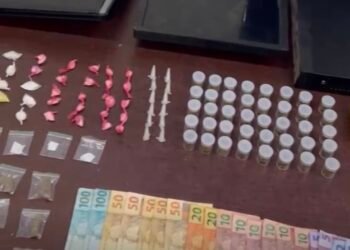 Polícia Militar apreende menor por tráfico em adega #PraCegoVer imagem mostra drogas, dinheiro, máquina de cartão e equipamentos de monitoramento apreendidos durante ocorrência policial