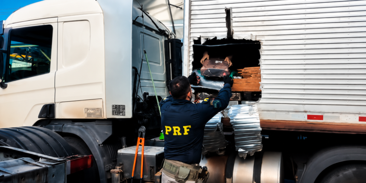 PRF apreende mais de 1 tonelada de maconha e prende homens do interior de SP #PraCegoVer: policiais rodoviários federais fiscalizam caminhão onde foram encontrados fardos de maconha escondidos em carga de ração.