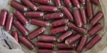 PM apreende cápsulas de cocaína na Marginal Tietê #PraCegoVer: imagem mostra várias cápsulas avermelhadas apreendidas dentro de uma sacola plástica branca sobre uma superfície clara.