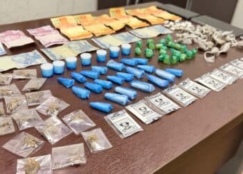 tráfico de drogas no Vida Nova #PraCegoVer: imagem mostra uma mesa com porções de drogas embaladas, dinheiro em notas e moedas, além de embalagens separadas para apresentação da ocorrência policial.
