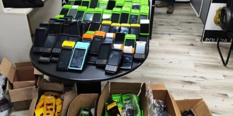 Operação Famulus contra grupo que desviava máquinas de cartão #PraCegoVer: policiais civis exibem máquinas de cartão, celulares e equipamentos apreendidos durante investigação contra organização criminosa.