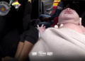 mãe boliviana dá à luz em carro de aplicativo. #PraCegoVer policial segurando recém-nascido